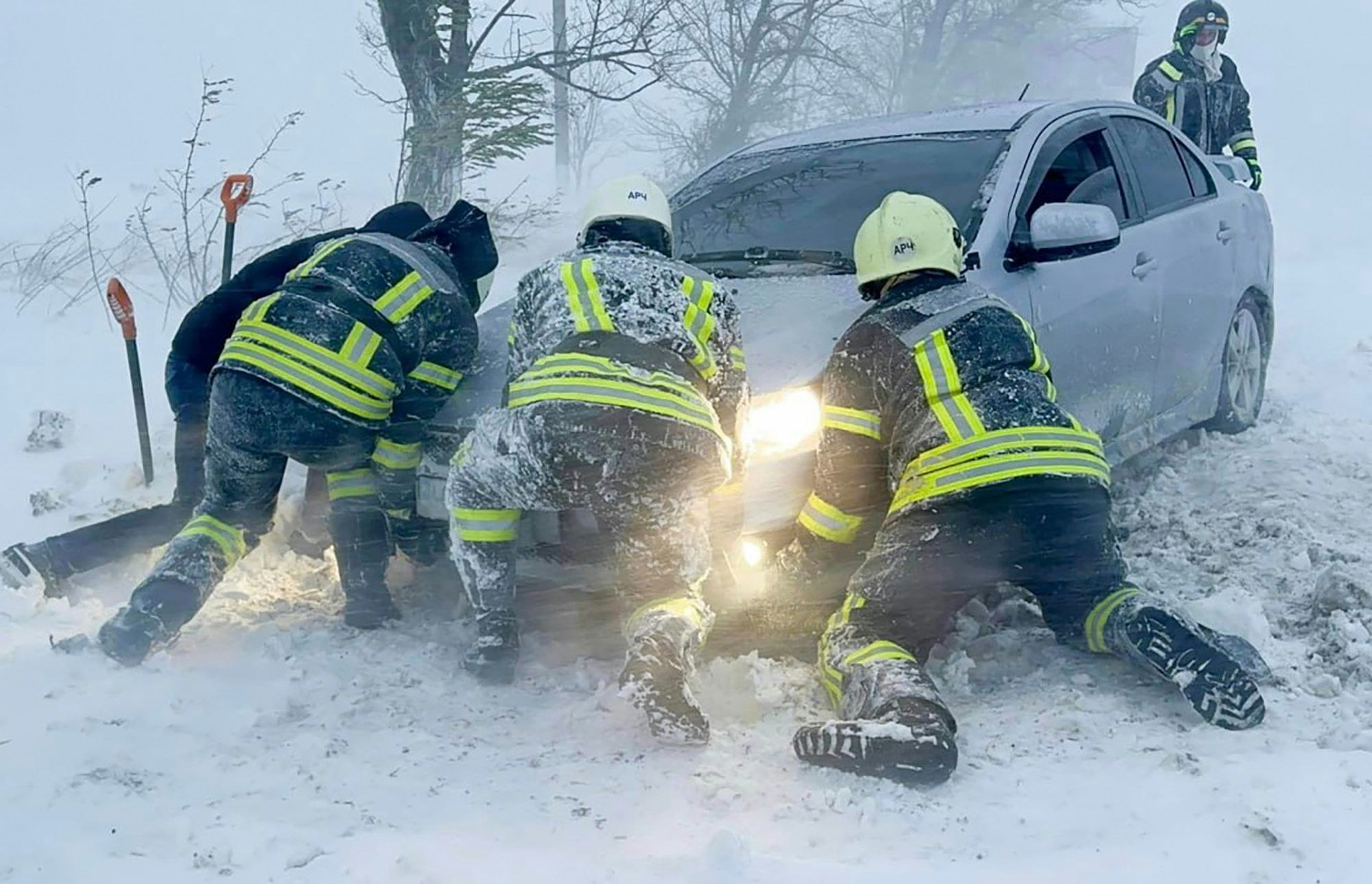 Auf diesem vom ukrainischen Rettungsdienst zur Verfügung gestellten Bild versuchen ukrainische Rettungskräfte ein im Schnee steckengebliebenes Auto auf der Autobahn in der Region Odessa zu schieben.