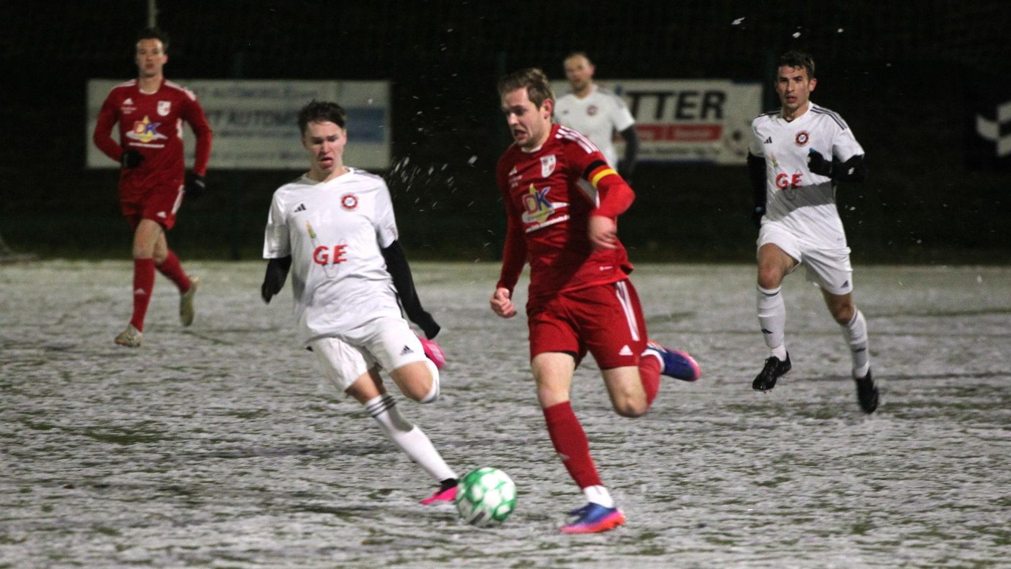 Ein Dahlemer Fußballer ist auf dem Schnee schneller als sein Frauenberger Gegenspieler.