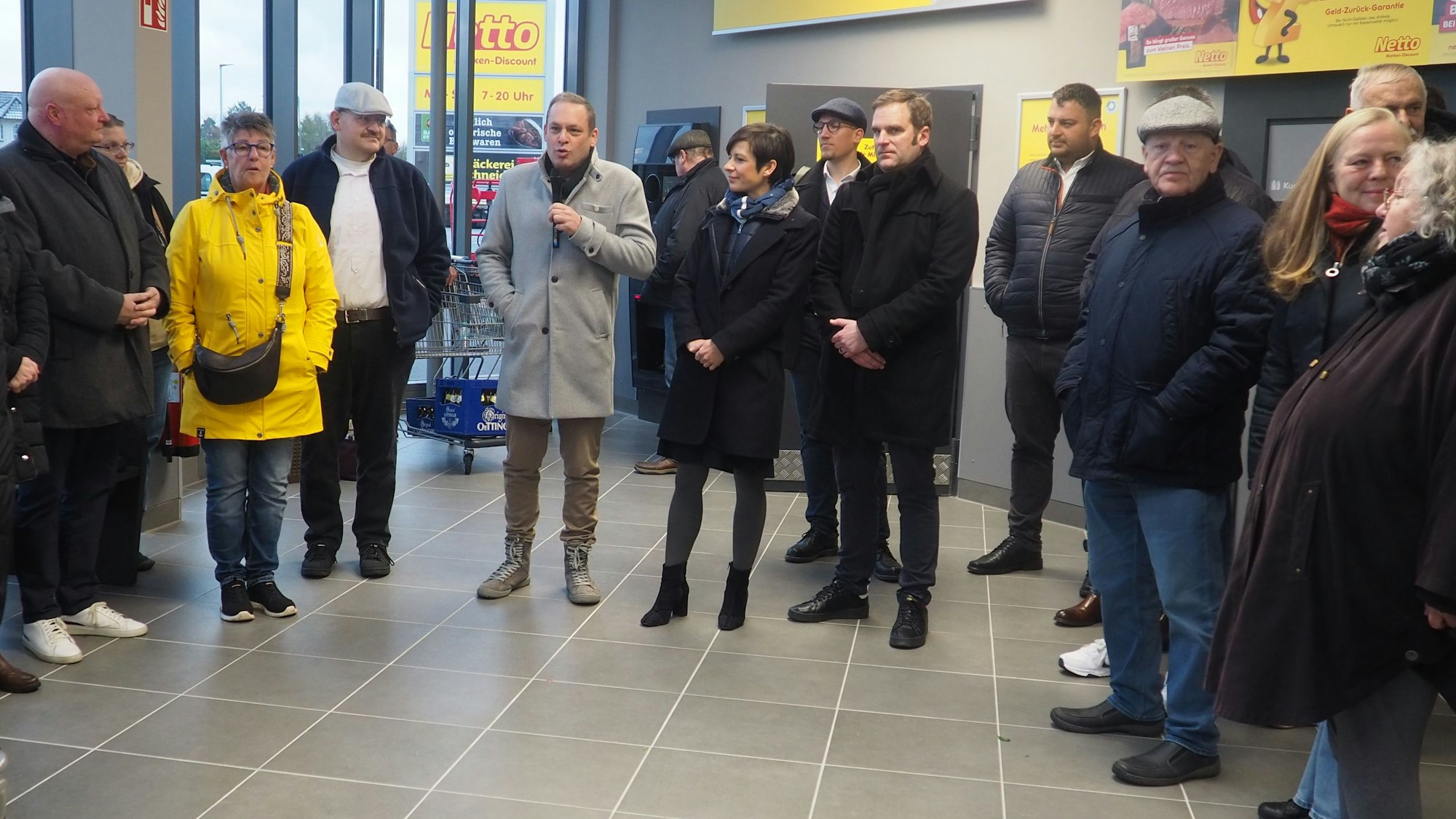 Eine Gruppe Menschen hat sich um einen Mann mit einem Mikrofon geschart.