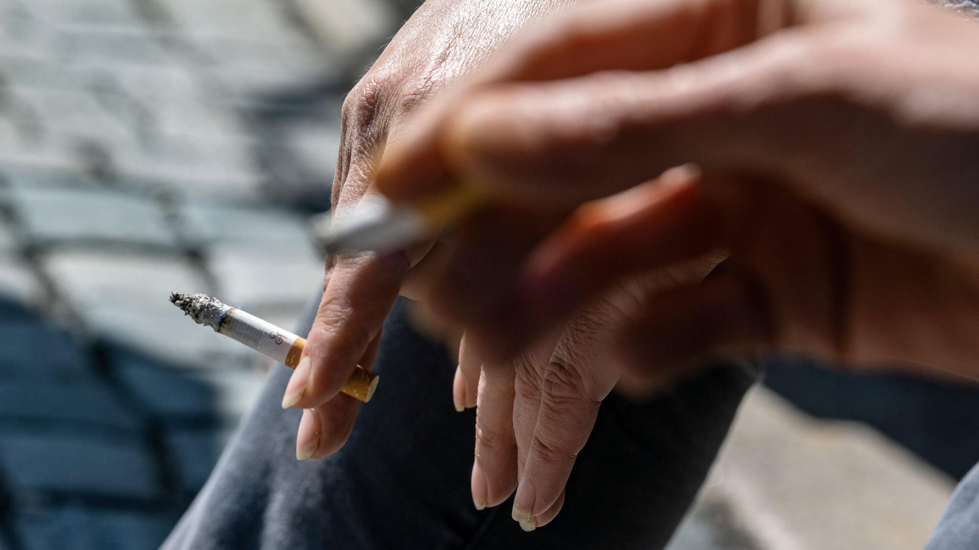 Raucher halten brennende Zigaretten in der Hand.