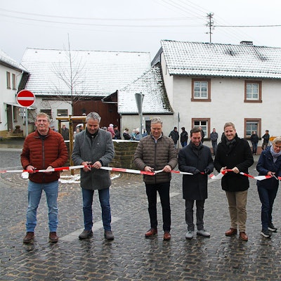 Vertreter aus Kreis, Gemeinde und Versorgern halten ein rot-weißes Flatterband in den Händen, das sie durchschneiden.