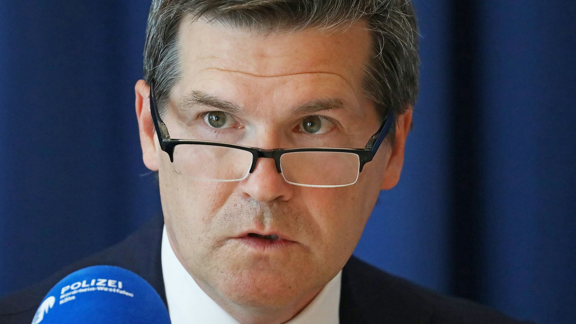 Ulrich Bremer, Oberstaatsanwalt in Köln, sitzt vor einem Polizeimikrofon.