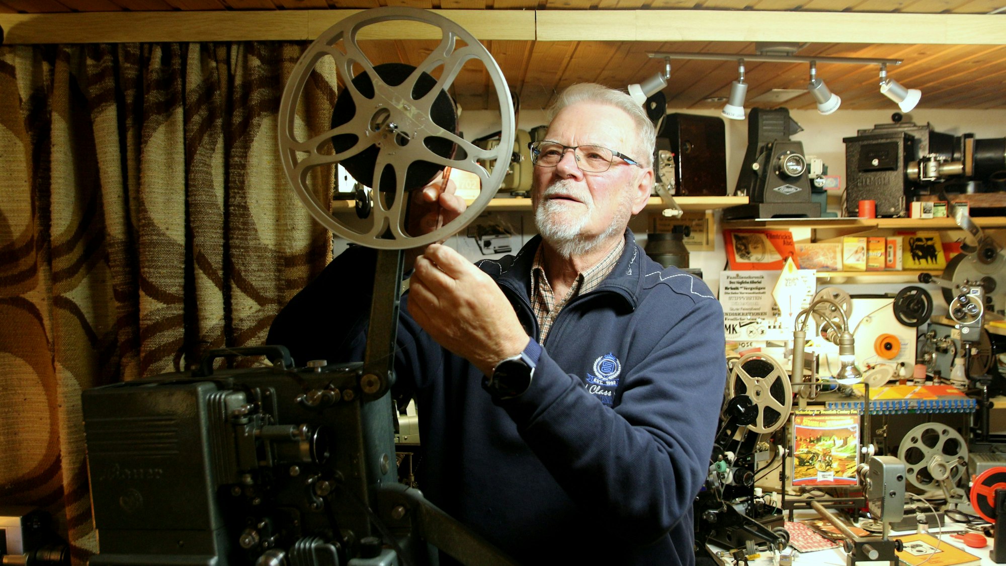 Auf dem Foto ist Peter Kleinen mit einem Filmprojektor zu sehen.
