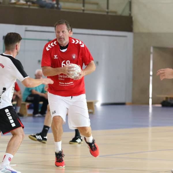 Zülpichs Spielertrainer Olaf Pohlmeier hat den Ball in der Hand, ein Gegner steht ihm gegenüber. Pohlmeier hat die Zunge rausgestreckt.