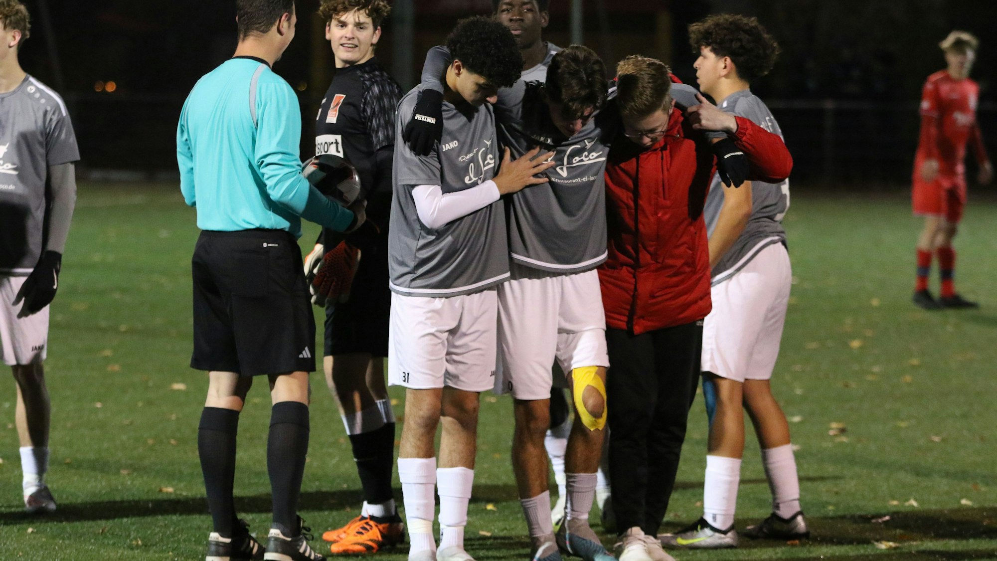 Spieler der JSG Erft 01 stützen ihren verletzten Kapitän und bringen ihn vom Feld.