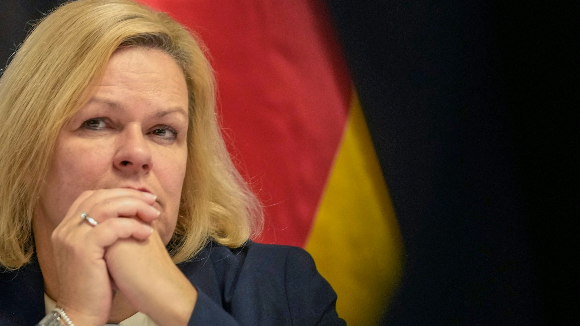 Nancy Faeser (SPD), Bundesministerin für Inneres und Heimat, mit gefalteten Händen, hinter ihr die Deutschlandfahne.