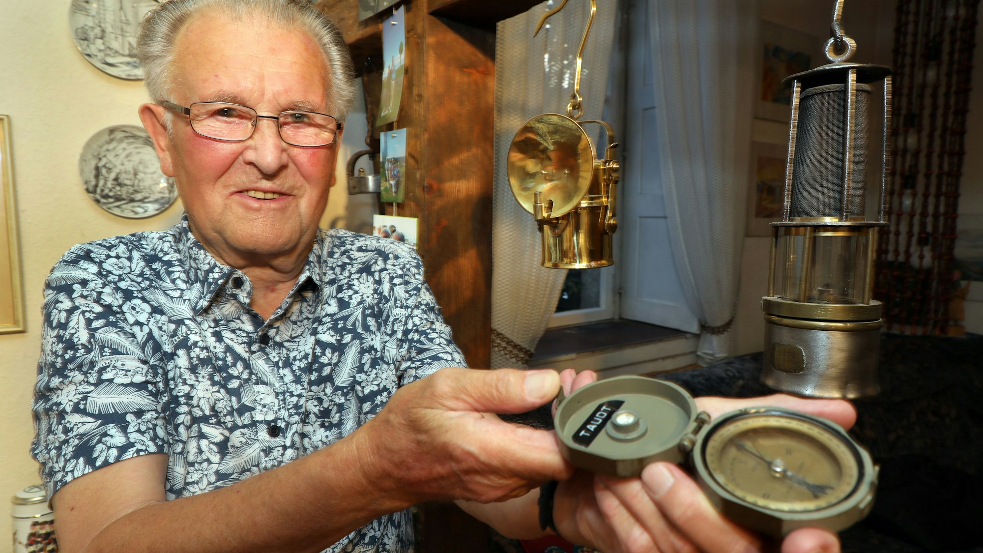 Ein Mann mit einem Kompass steht vor Bergleuchten in einem Wohnzimmer.