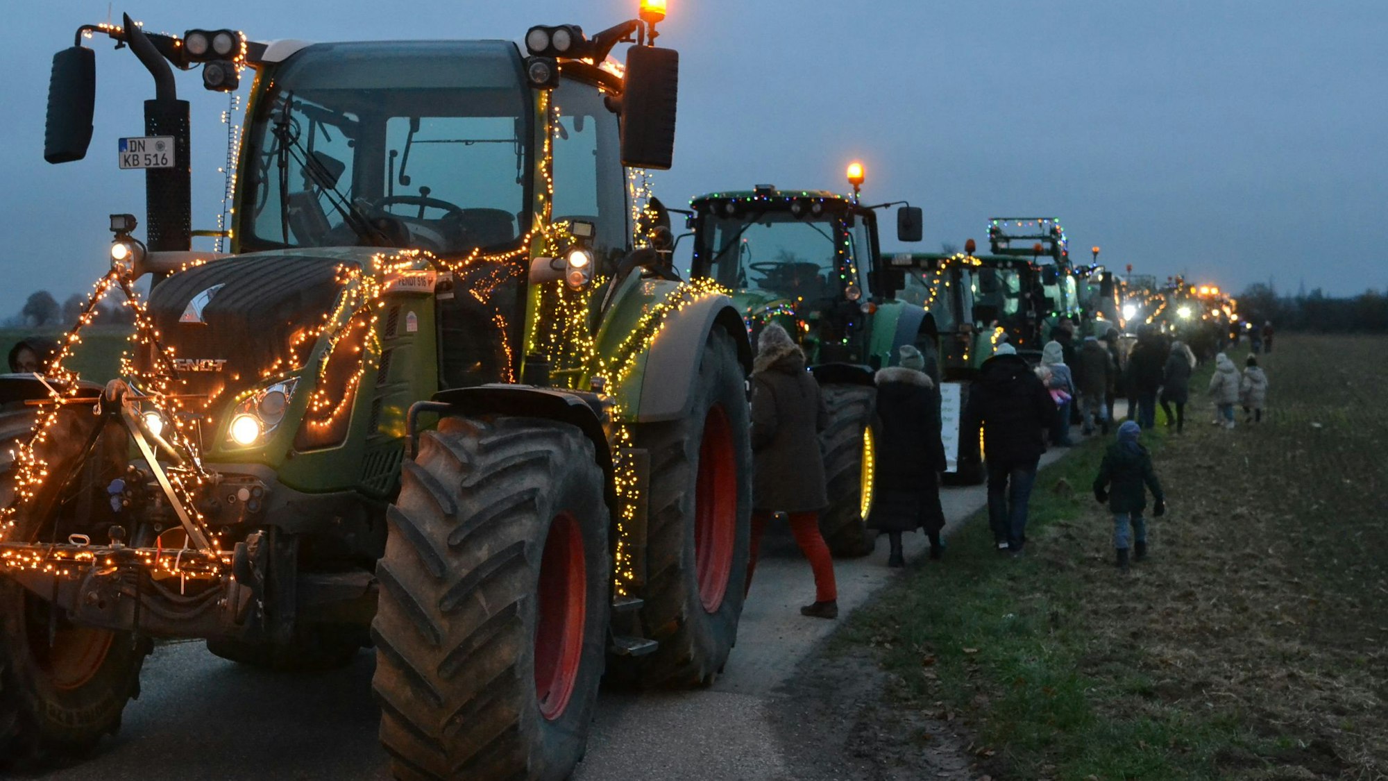Das Bild zeigt einige Traktoren auf einem Wirtschaftsweg. Sie sind mit Lichterketten geschmückt.