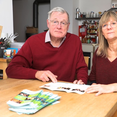 Der Vorsitzende des Kulturforums Overath, Jürgen Wesche, und Vize-Vorsitzende Margret Altemeier sitzen mit sorgenvoller Miene an einem Tisch und halten das Programm des Kulturforums in den Händen.