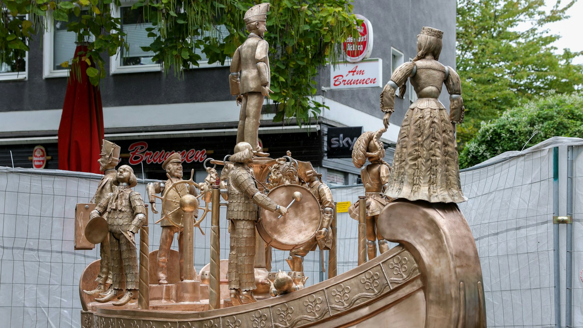 Ein bronzefarbender Brunnen mit mehreren Figuren