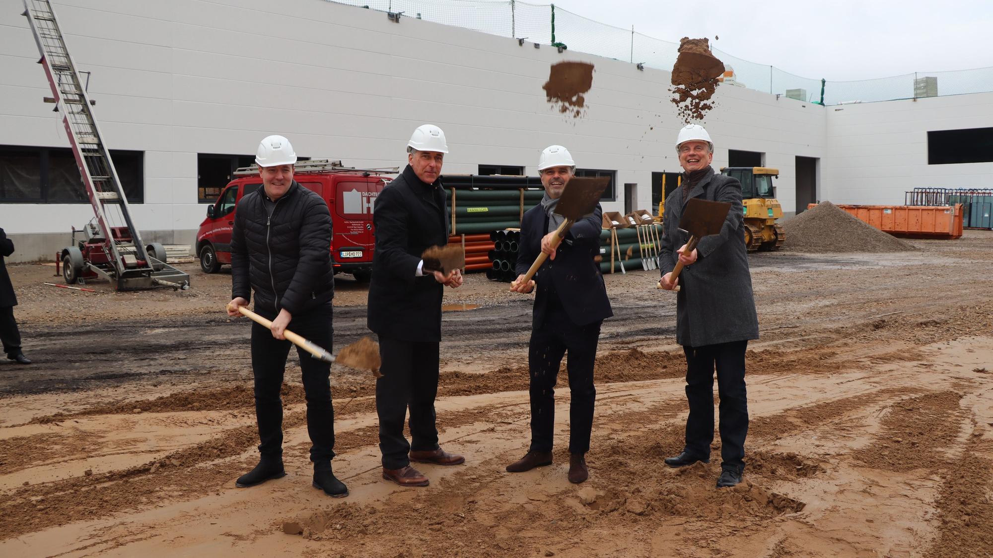 Auf dem Foto sind vier Männer mit Schaufeln beim ersten Spatenstich für das Renault-Schulungszentrum in Wesseling zu sehen.