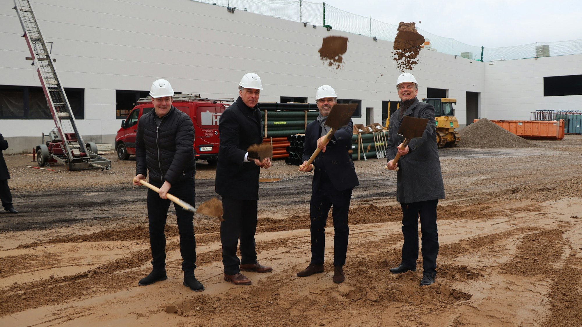 Auf dem Foto sind vier Männer mit Schaufeln beim ersten Spatenstich für das Renault-Schulungszentrum in Wesseling zu sehen.