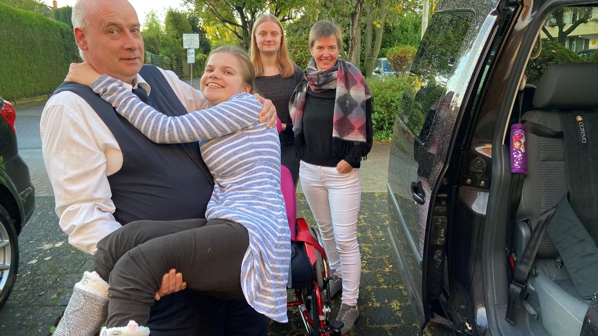 Auf dem Bild ist Lauras Vater zu sehen, der seine Tochter in das Auto hebt.