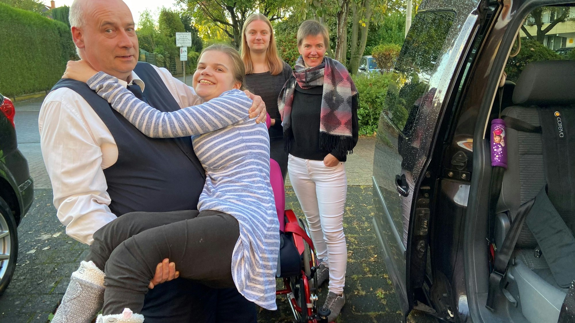 Auf dem Bild ist Lauras Vater zu sehen, der seine Tochter in das Auto hebt.
