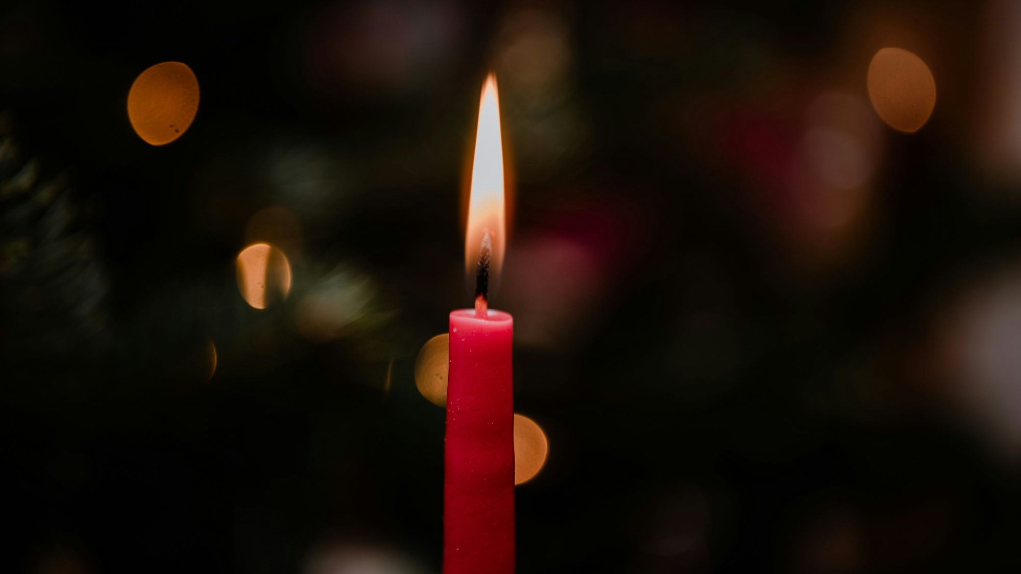 Eine rote Kerze brennt in der Dunkelheit.