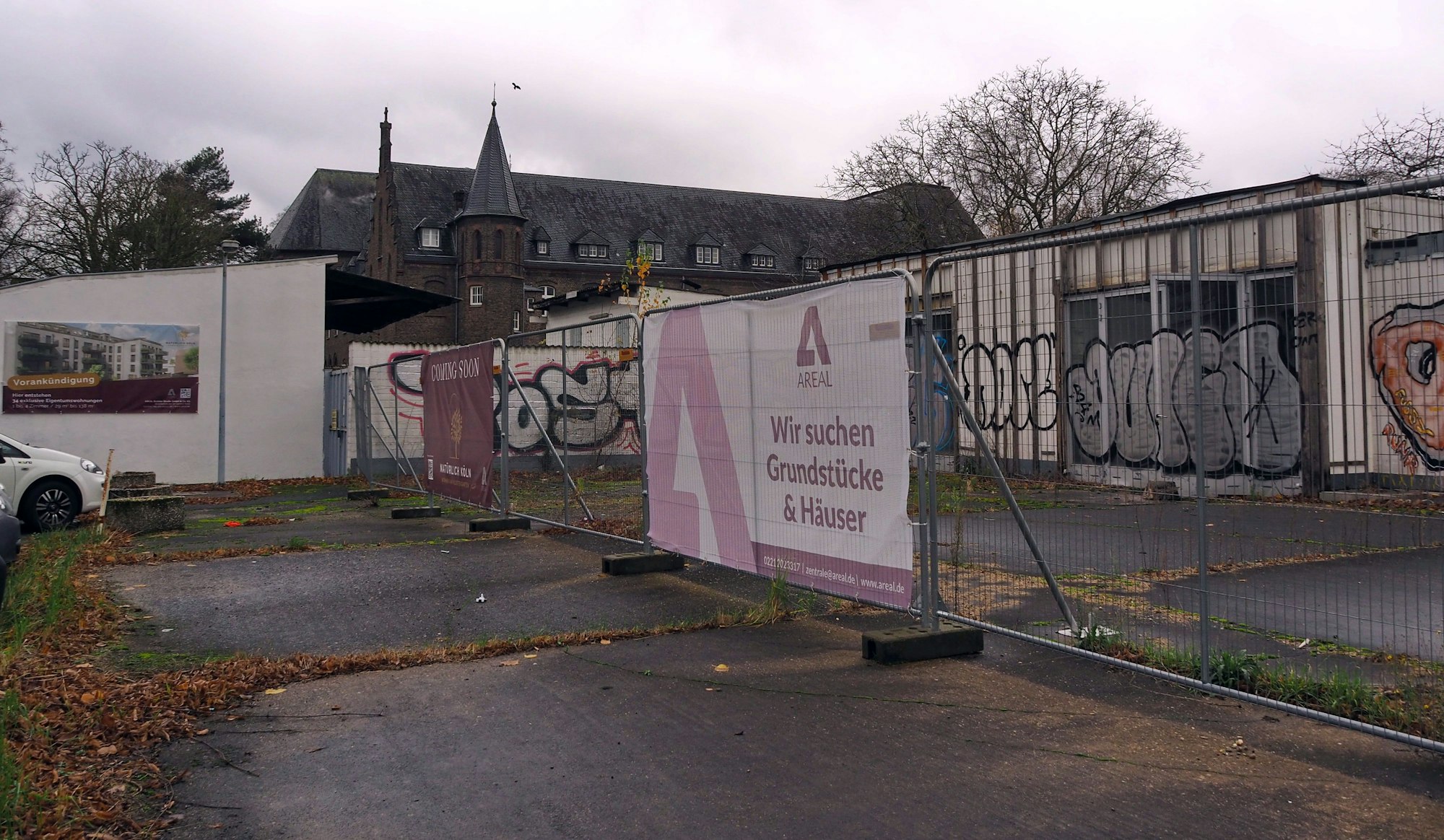 Das Grundstück an der Brühler Straße hinter einem Bauzaun. Im Hintergrund ist das Kloster der Benediktinerinnen zu sehen.