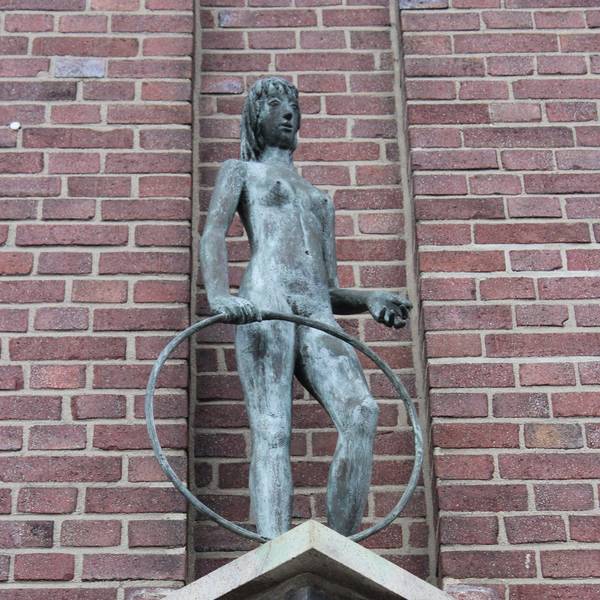 Das Bild zeigt die Skulptur eines Mädchens, das einen Reifen in der Hand hält.