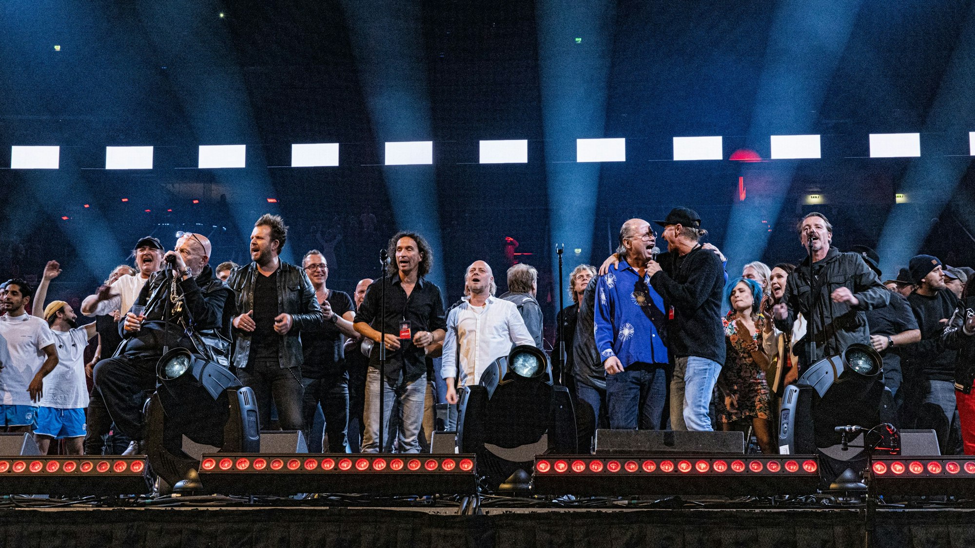 Musiker stehen auf einer Bühne und singen gemeinsam.