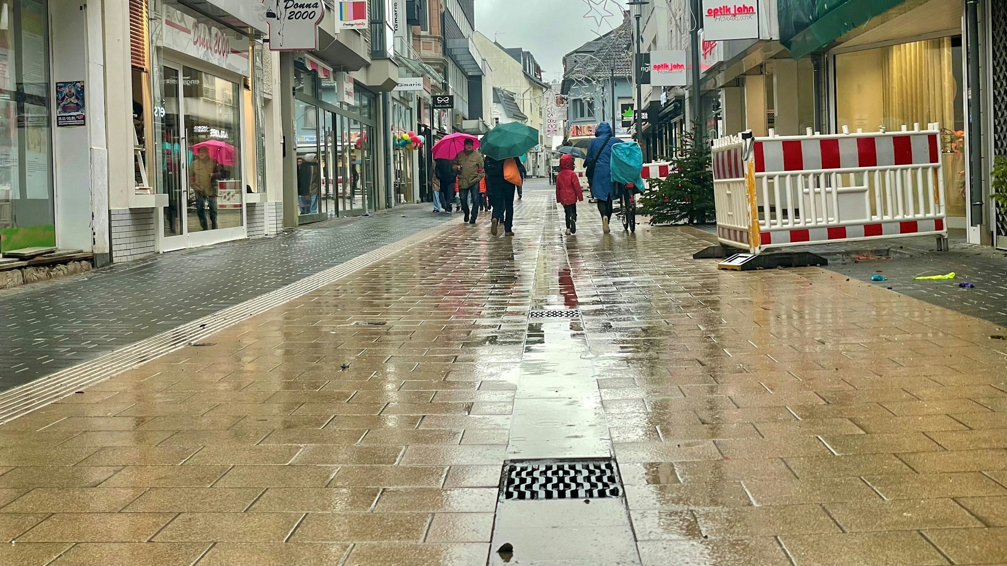 Das Bild zeigt die Neustraße bei Regen. Vor dem Abfluss bleibt das Wasser mitunter ein wenig stehen.