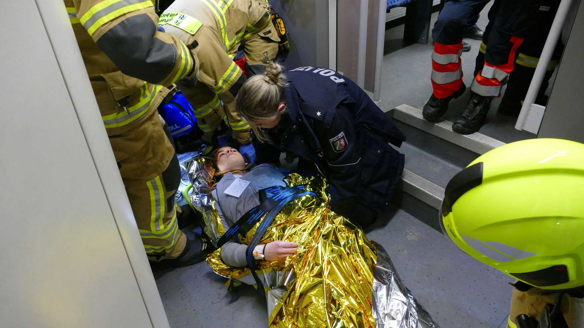 Feuerwehrleute und eine Polizistin hieven eine verletzte Frau auf einer Trage durch den Zug.