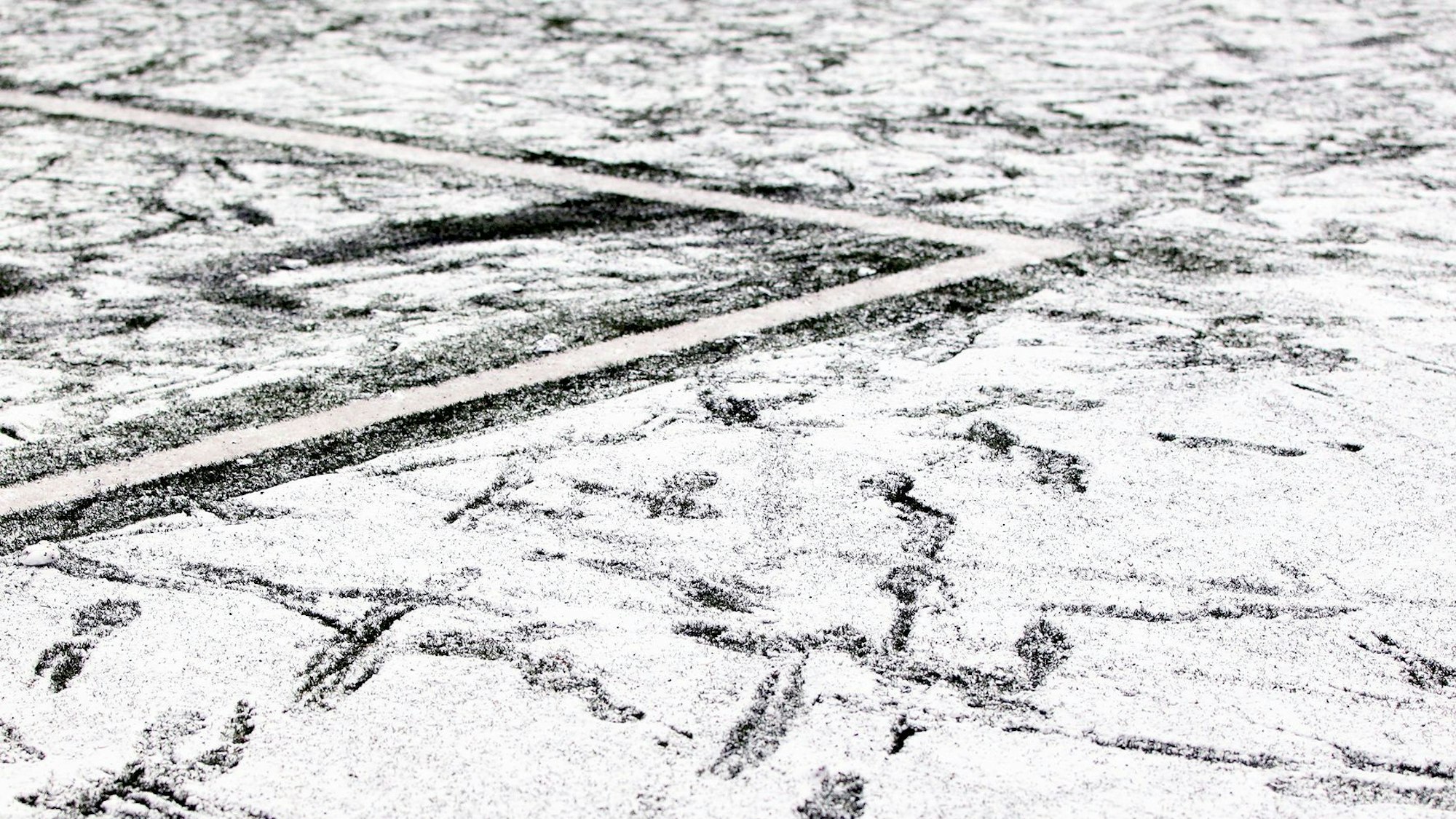 Die Ecke eines Strafraums auf einem Kunstrasenplatz ist schneebedeckt.