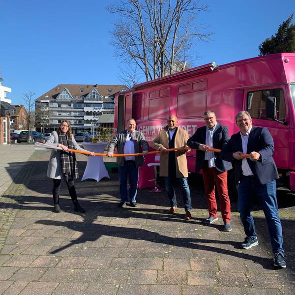 Vertreter der Stadt Niederkassel und der Telekom halten ein dickes Glasfaserkabel in der Hand. Im Hintergrund steht ein magentafarbenes Infomobil der Telekom.