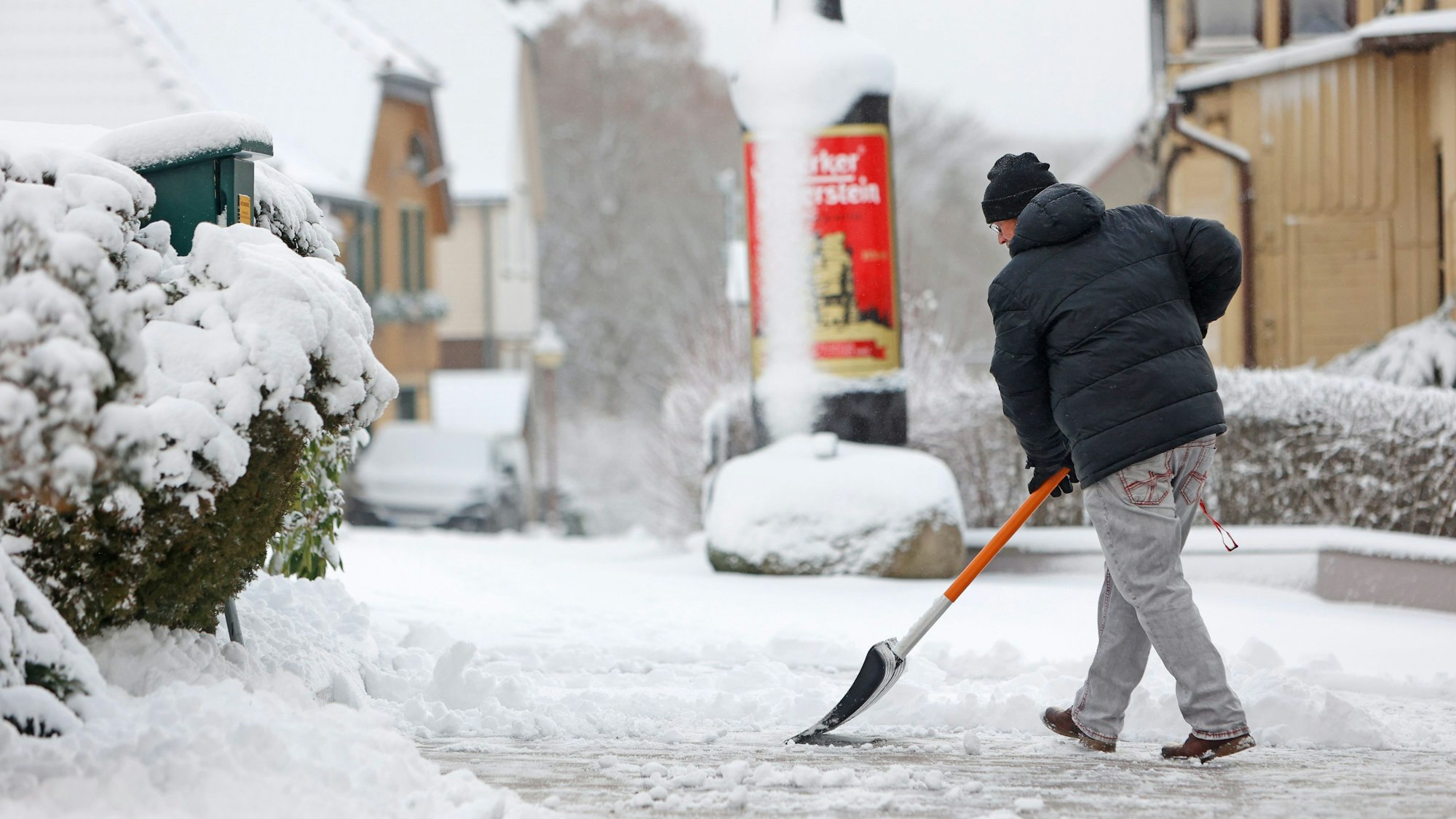 Ein Mann schiebt Schnee vom Gehweg.