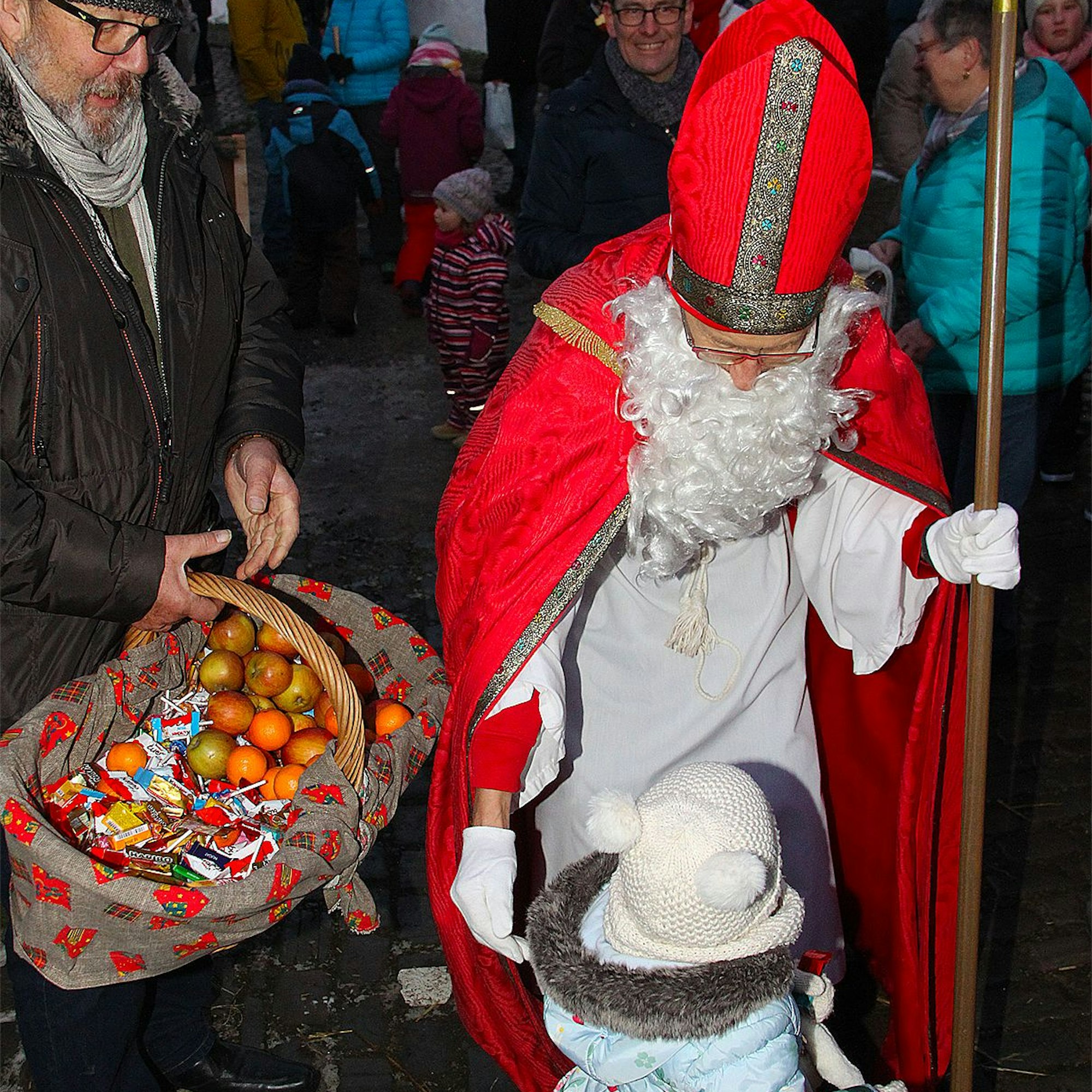 Nikolaus Heinz-Bert Weimbs erfreut ein kleines Kind mit einem Geschenk aus einem großen Korb.