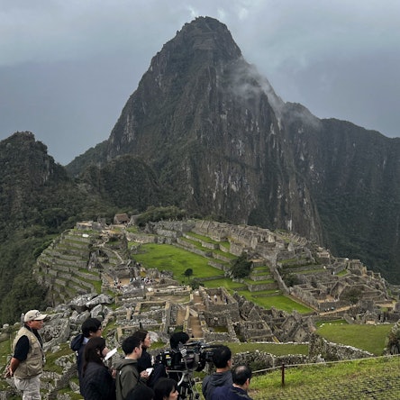 Eine Gruppe von Touristen steht am Rande des Machu Picchu in Peru.