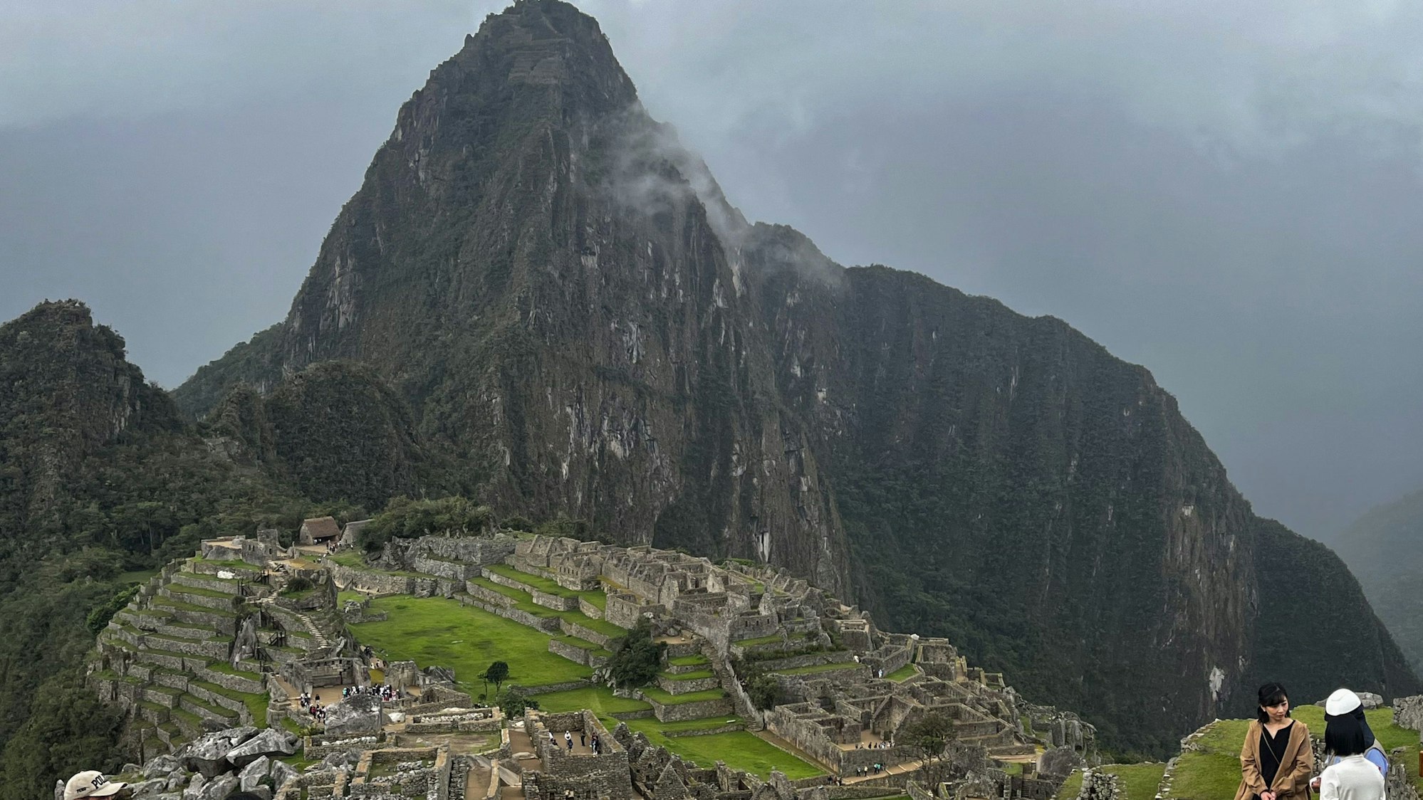 Eine Gruppe von Touristen steht am Rande des Machu Picchu in Peru.