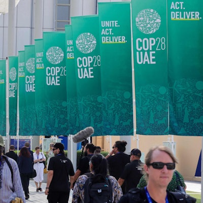 Participants walk past banners at the COP28 United Nations climate summit in Dubai on December 3, 2023. (Photo by Giuseppe CACACE / AFP)