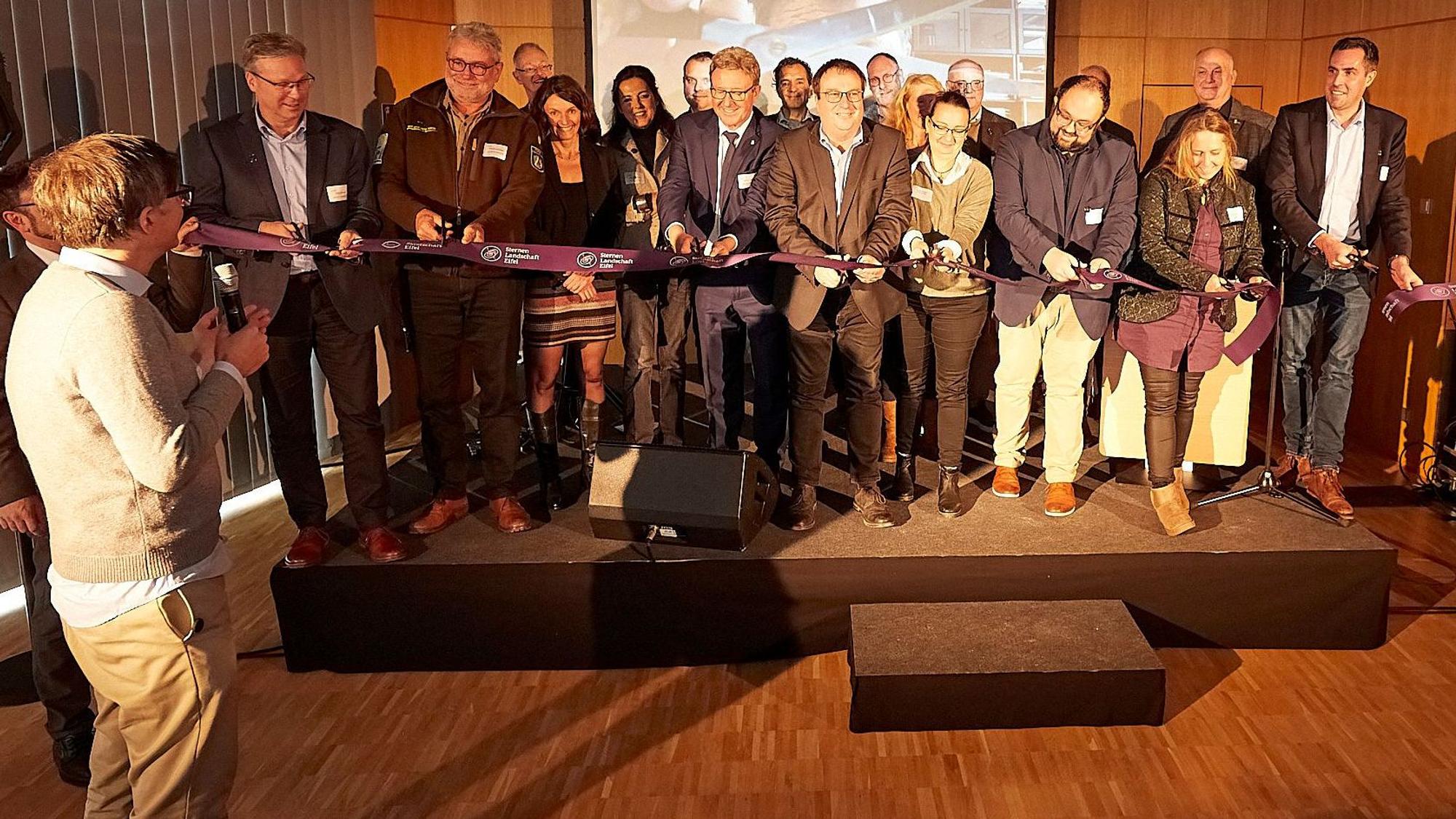 Eine Gruppe steht hinter einem Band, das NRW-Umweltminister Oliver Krischer und andere durchschneiden. Schirmherr und Moderator Ralph Caspers steht davor und gibt das Startzeichen.