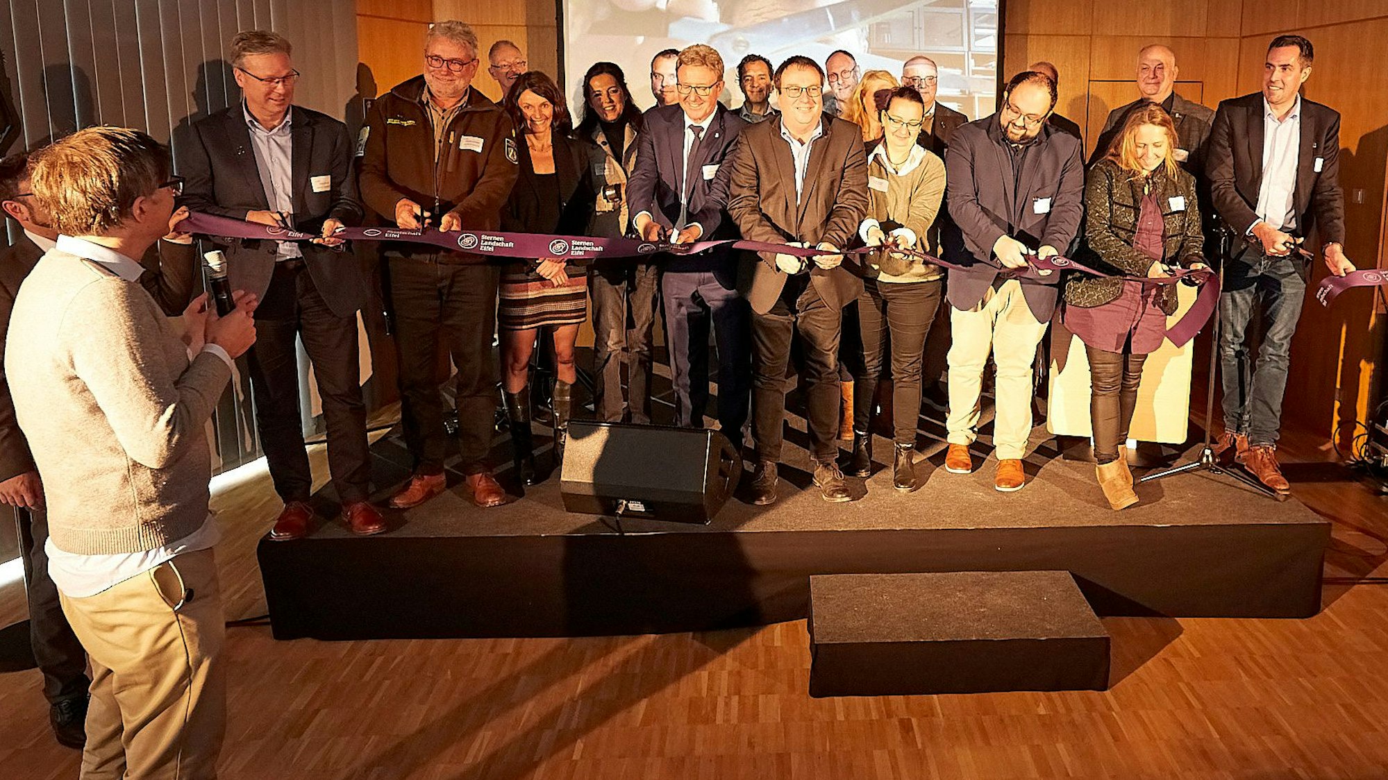 Eine Gruppe steht hinter einem Band, das NRW-Umweltminister Oliver Krischer und andere durchschneiden. Schirmherr und Moderator Ralph Caspers steht davor und gibt das Startzeichen.