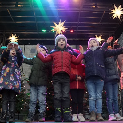 Kinder stehen auf einer weihnachtlich geschmückten Bühne.
