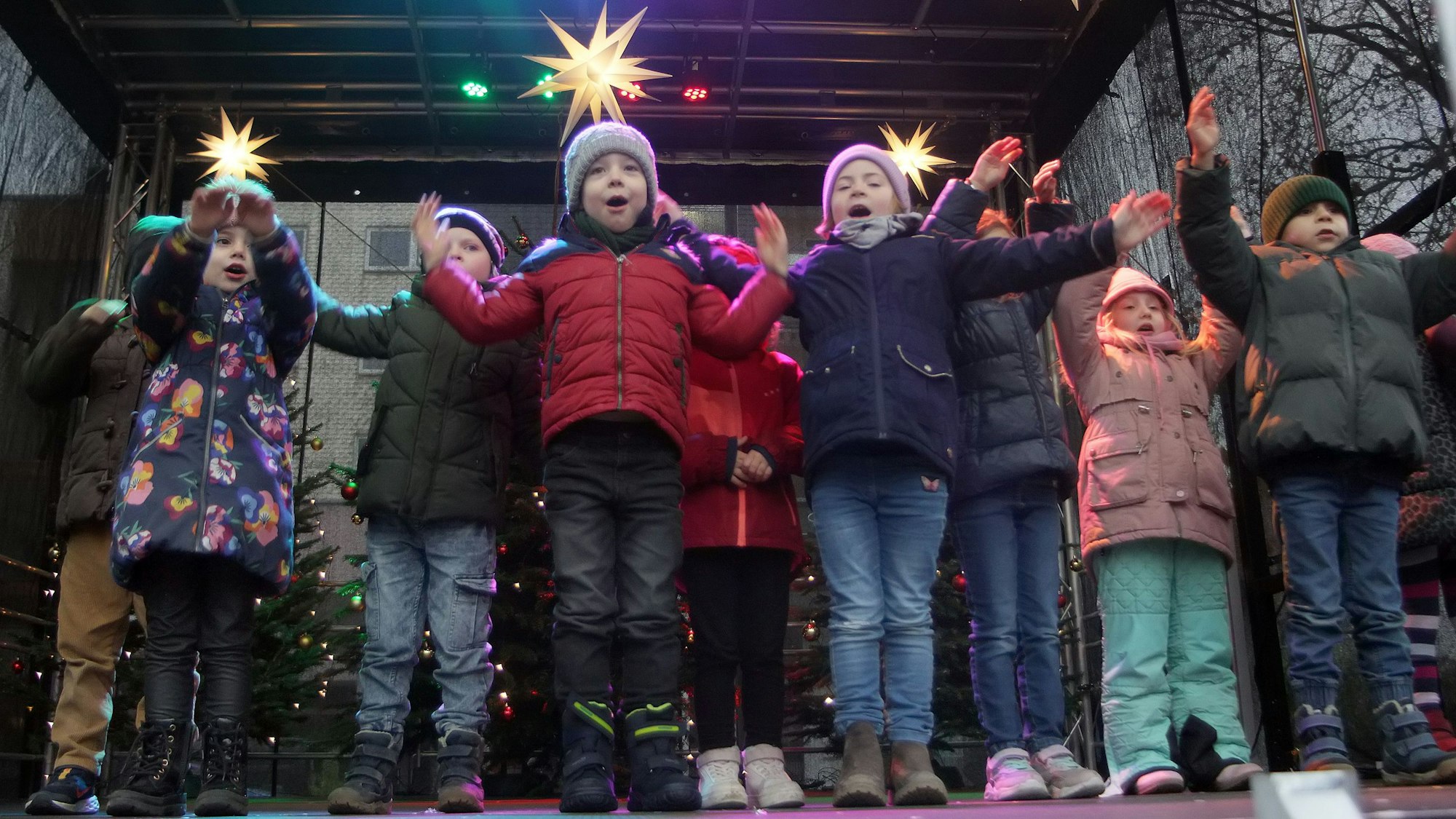 Kinder stehen auf einer weihnachtlich geschmückten Bühne.