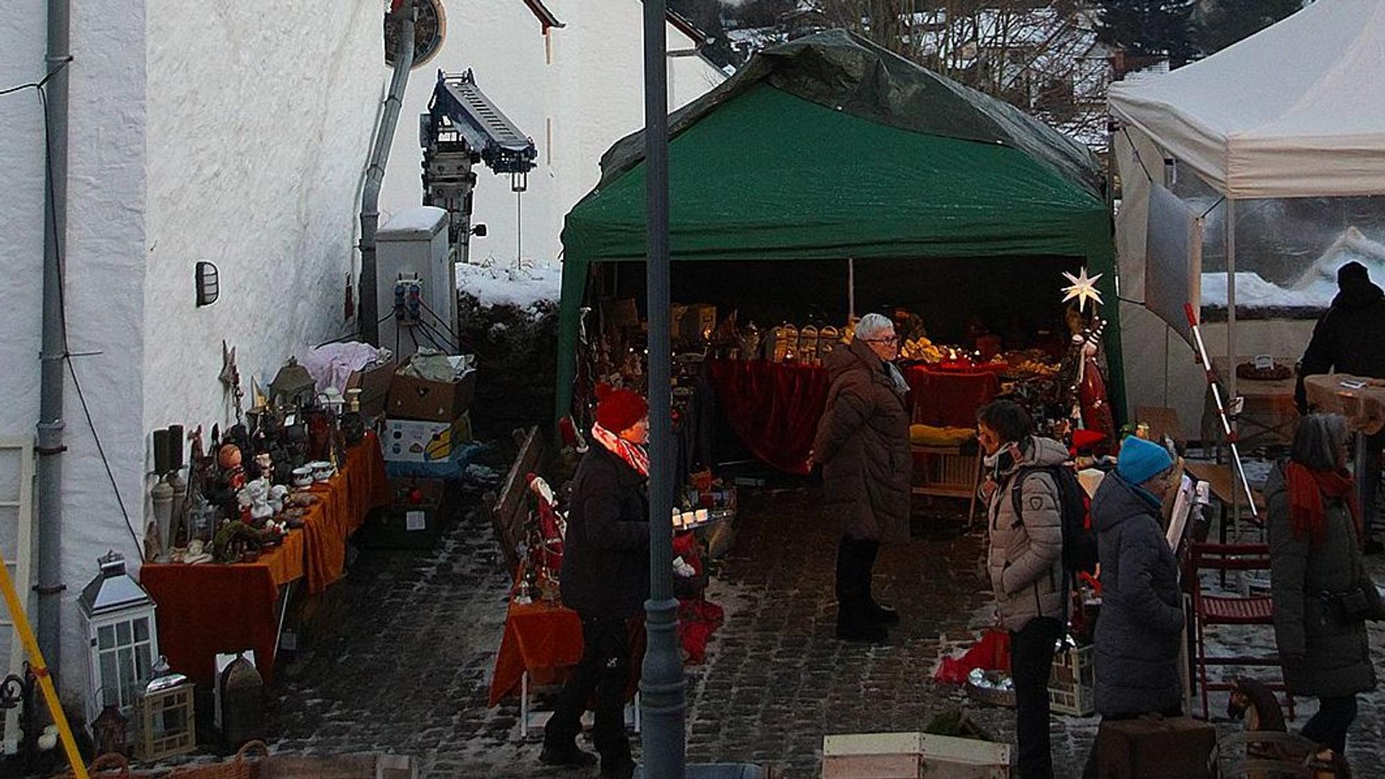 Das Bild zeigt im Vordergrund einen Teil es Weihnachtsmarkts, im Hintergrund ist die verschneite Landschaft zu sehen.
