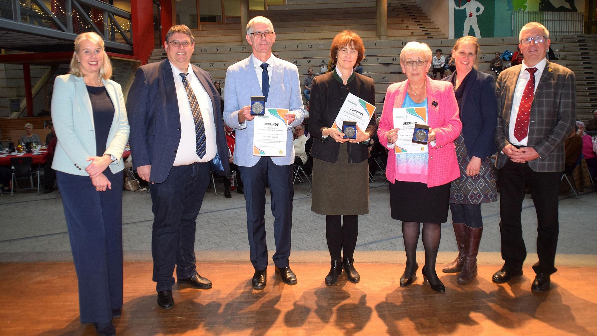 Sabine Hübel, Michael Söllheim (links) und Alice von Bülow, Christoph Becker (rechts) stehen neben den ersten Preisträgern der Ehrenamtsmedaille (von links) Hans-Dieter Günther, Isabelle Lütz und Marie-Therese van den Bergh. Die halten ihre Urkunden in den Händen.
