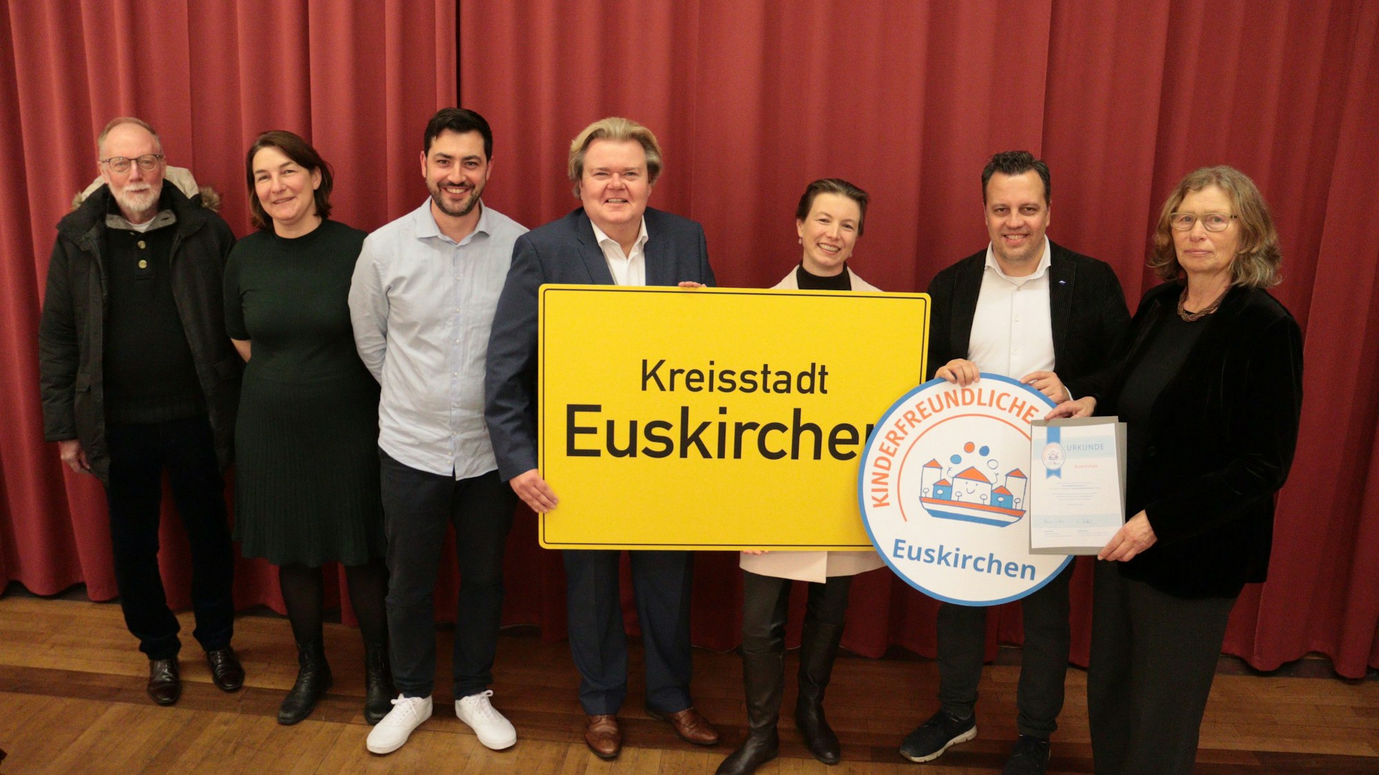 Frauen und Männer, die an der Übergabe des Siegels „Kinderfreundliche Kommune“ an die Stadt Euskirchen teilnahmen, stehen im Ratssaal nebeneinander.