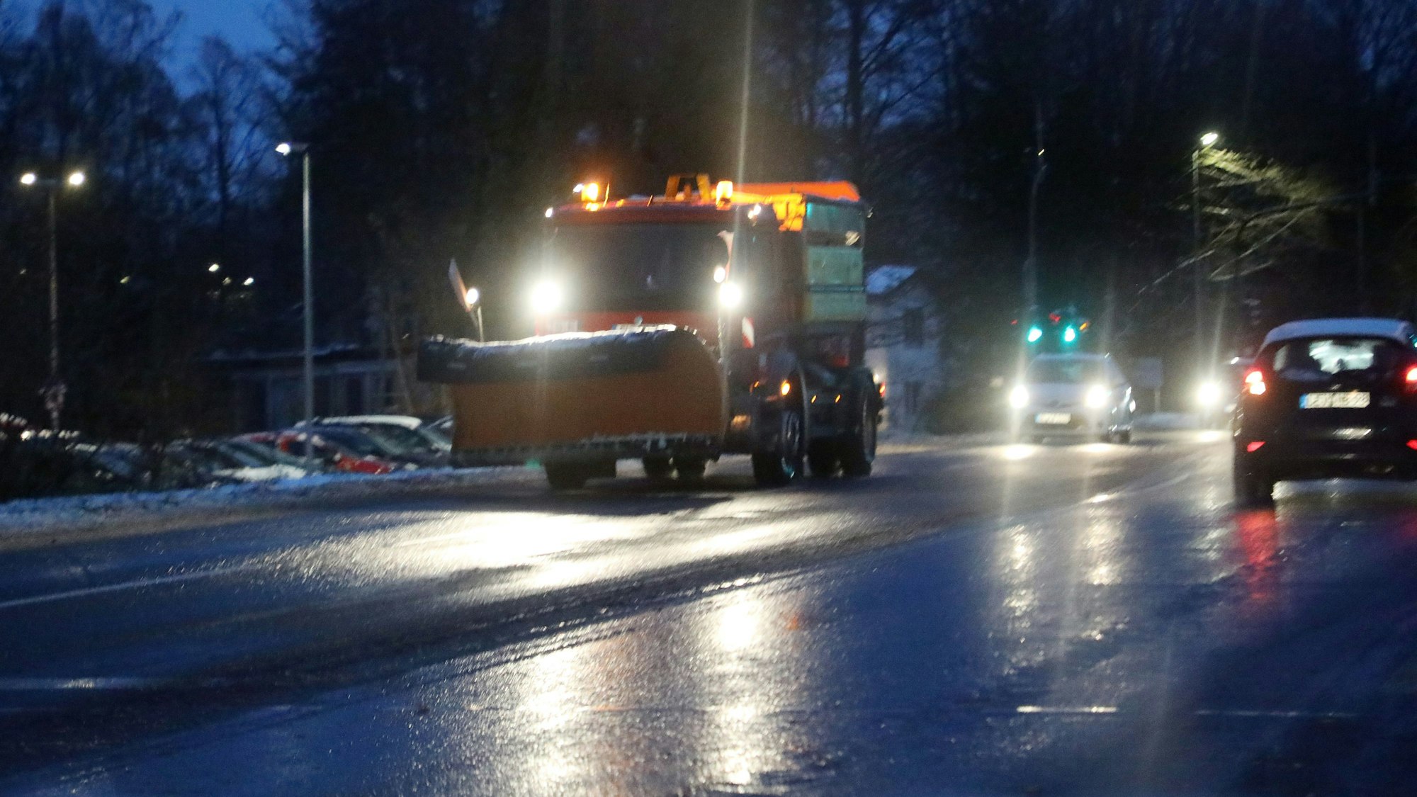 Ein Streu- und Räumfahrzeug fährt mit gelbem Rundumlicht auf einer winterlicher Straße.