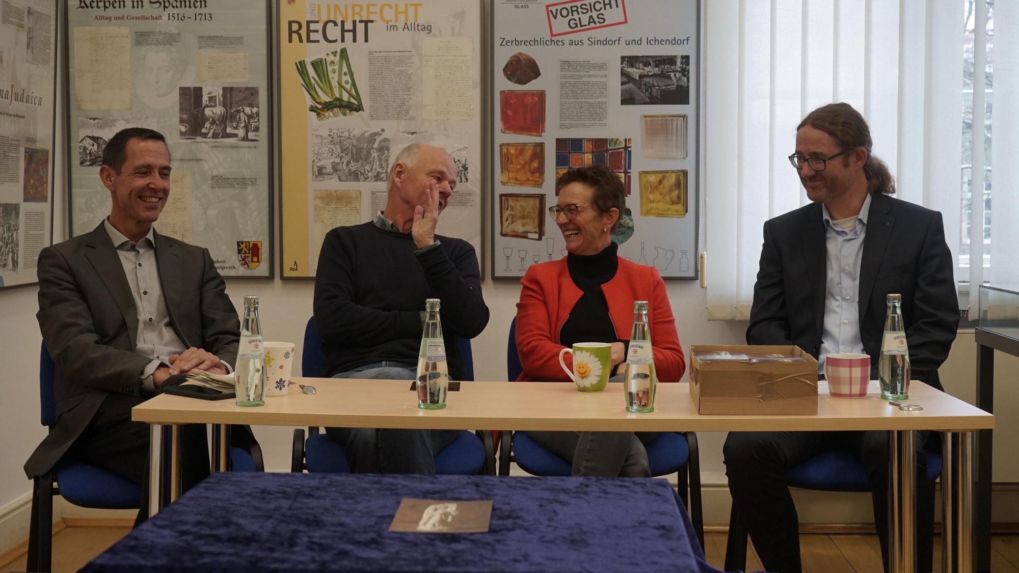 Auf dem Bild sitzen Bürgermeister Dieter Spürck, Martin Heinen (Geschäftsführer des Grabungsunternehmens Arthemus), Stadtarchivarin Susanne Harke-Schmidt und Martin Grünewald (LVR-Amt für Bodendenkmalpflege) an einem Tisch im Haus für Kunst und Geschichte.