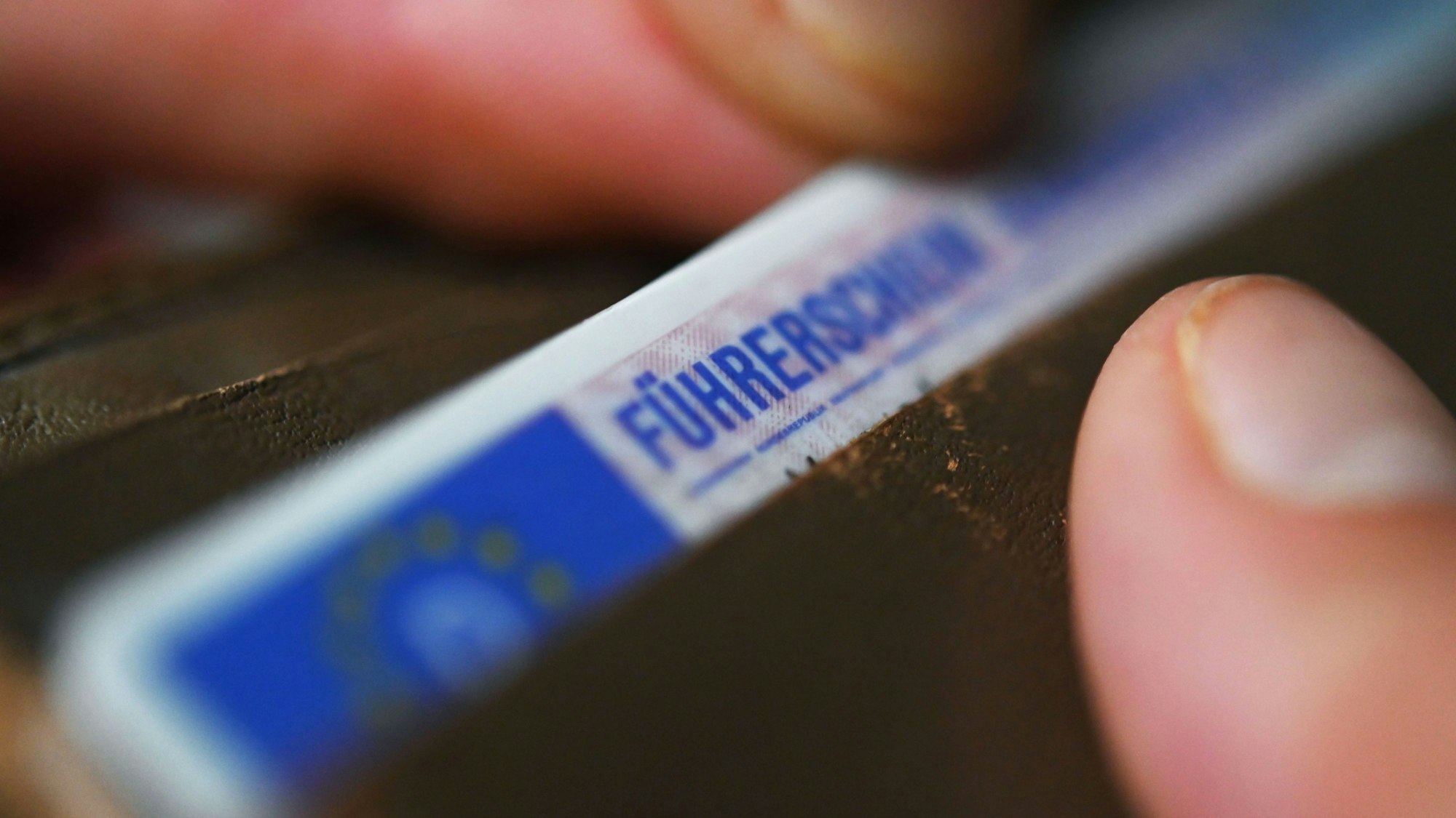 Eine Frau nimmt einen Führerschein im EU-Scheckkartenformat aus ihrem Geldbeutel.