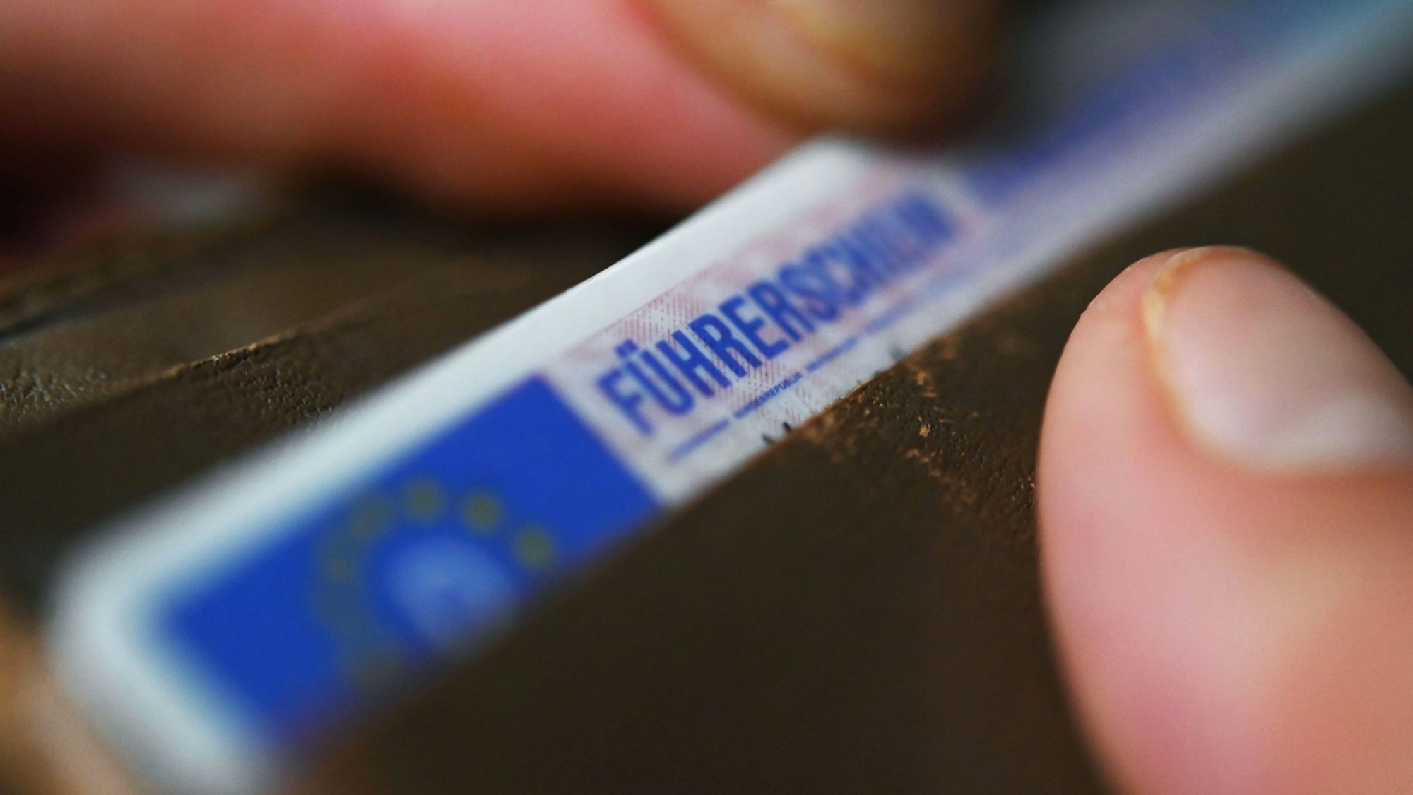 ARCHIV - 11.09.2023, Baden-Württemberg, Stuttgart: Eine Frau nimmt einen Führerschein aus ihrem Geldbeutel.