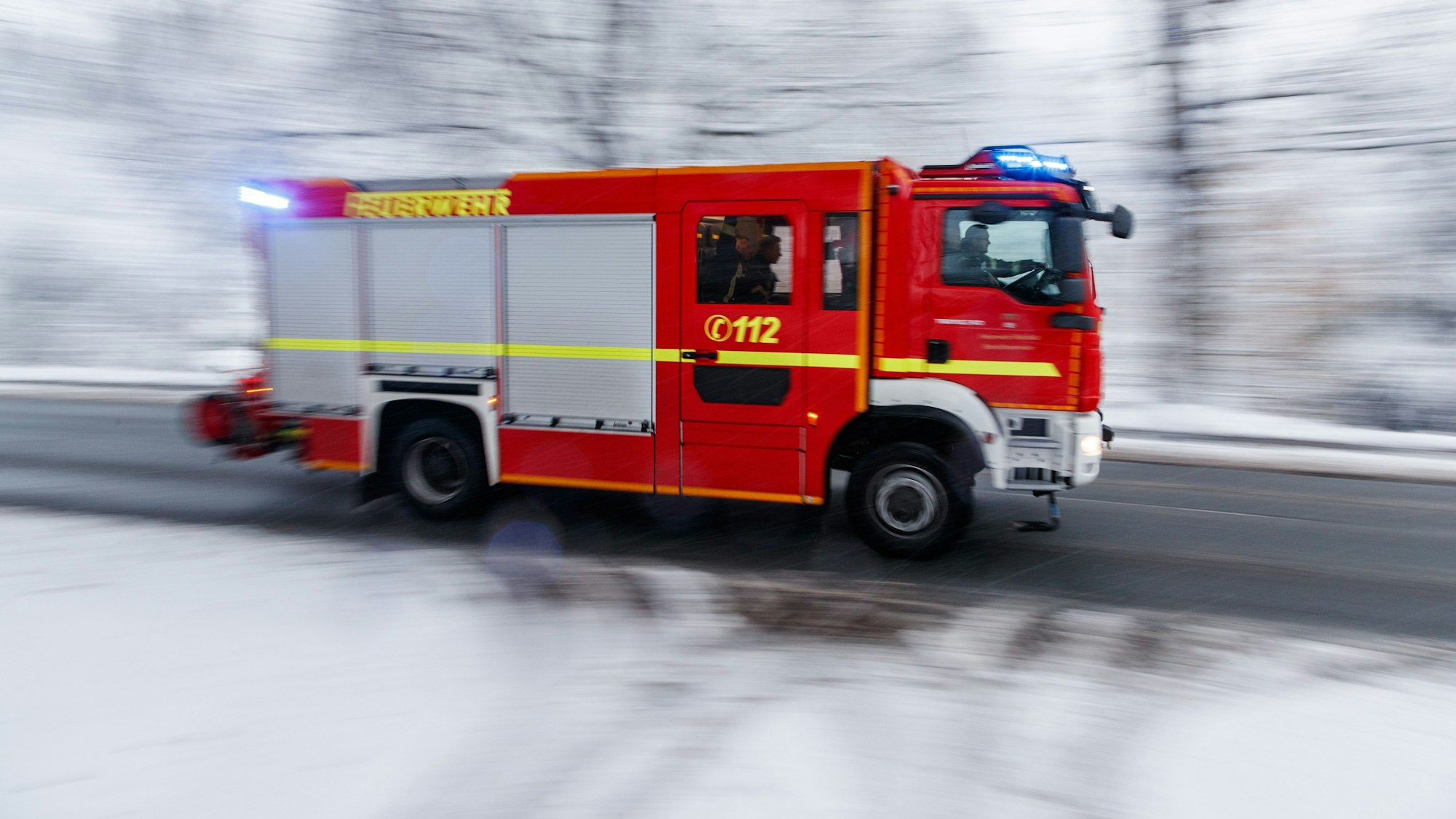 Feuerwehrfahrzeug auf verschneiter Straße.