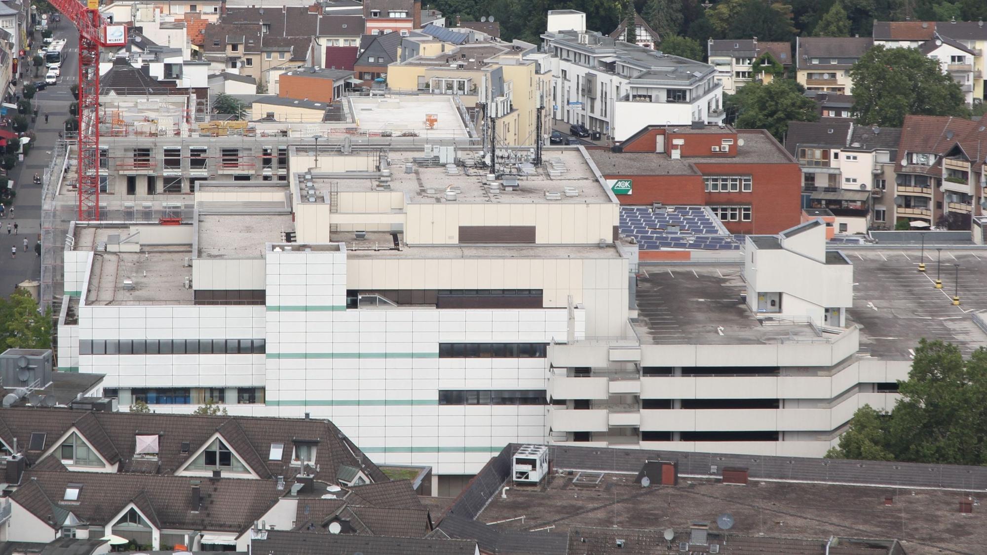 Ein Kaufhaus und ein Parkhaus mit hellen Betonfassaden aus der Vogelperspektive