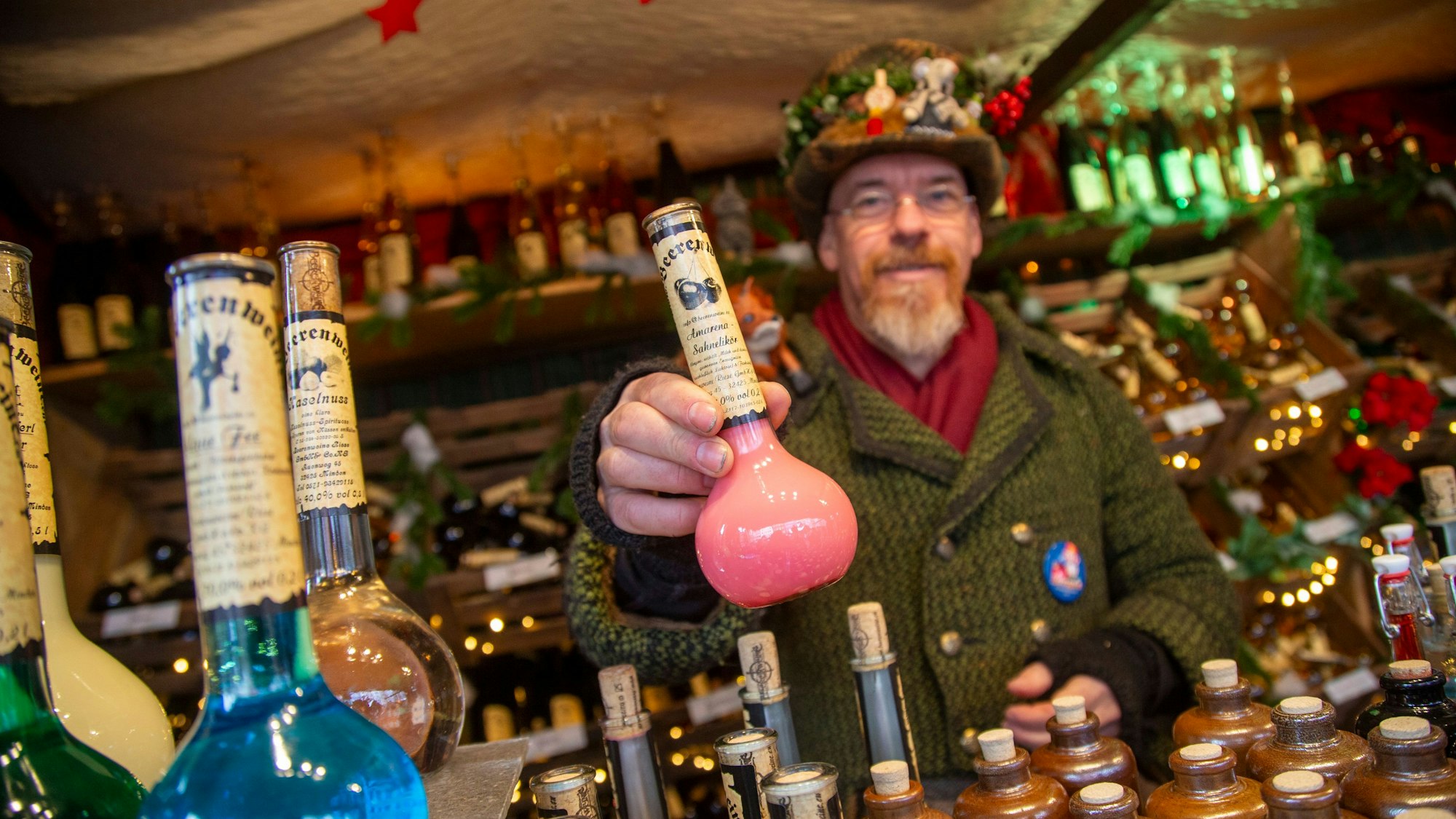 Ein Mann zeigt eine rosa Likör-Flasche.