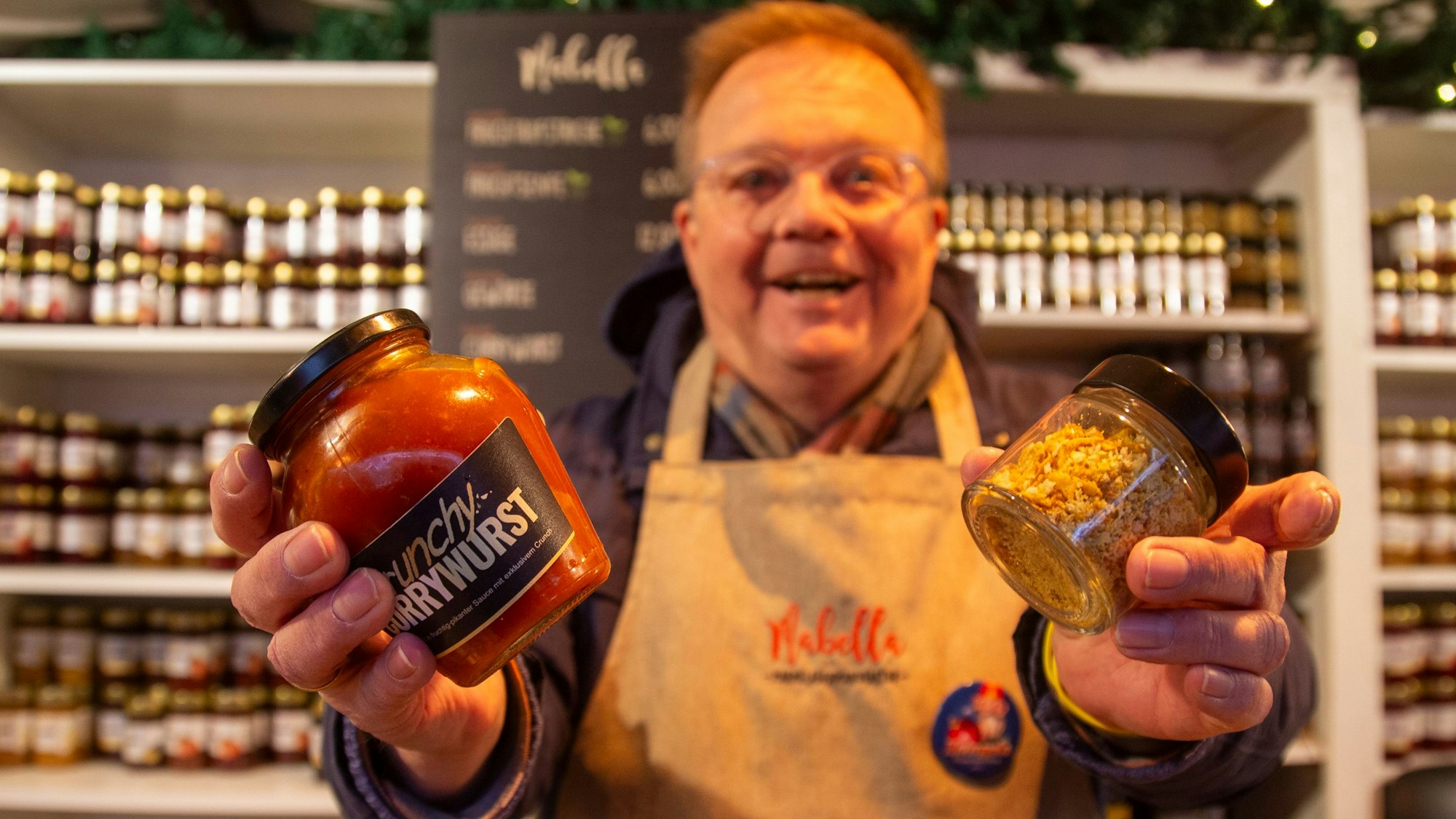 Ein Mann zeigt ein Einmachglas mit rotem Inhalt.