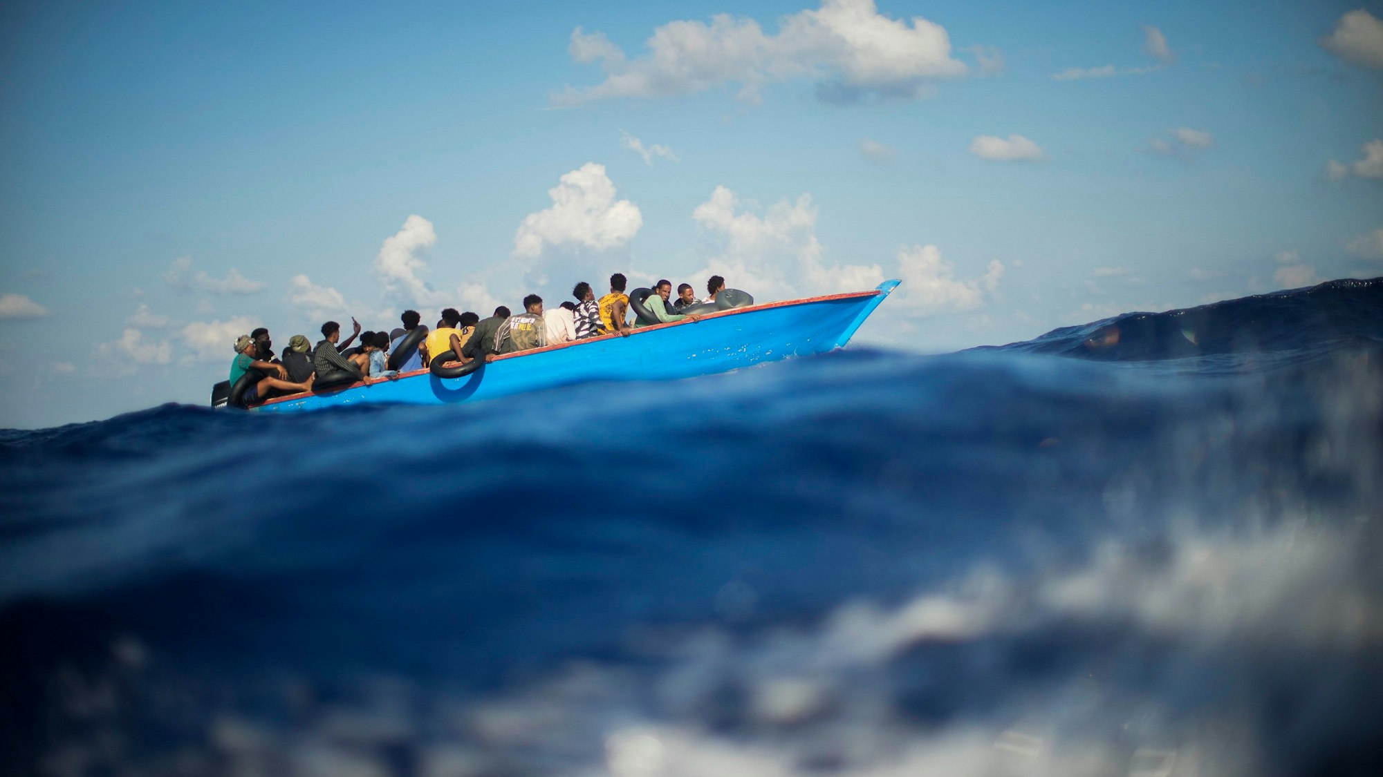 Migranten sitzen in einem Holzboot im Mittelmeer.