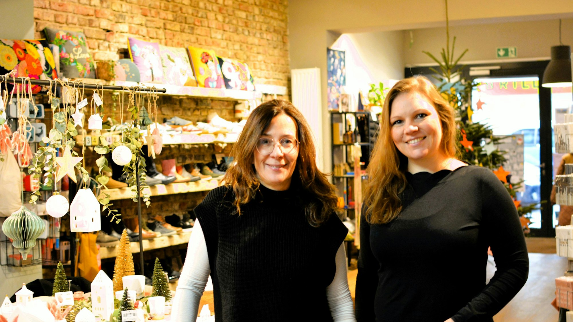 Heike Sommnitz und Lisa Schlömer stehen in einem Laden mit weihnachtlichen Deko-Artikeln und Schuhen.