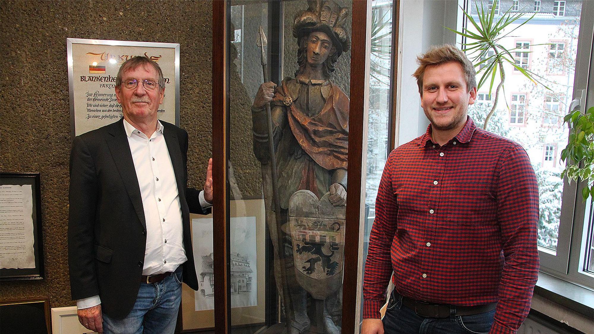 Erwin Nelles (links) und Robin Poensgen stehen an der Vitrine im Blankenheimer Rathaus, in der die Figur des heiligen Nepomuk mit dem Wappen aufbewahrt wird.