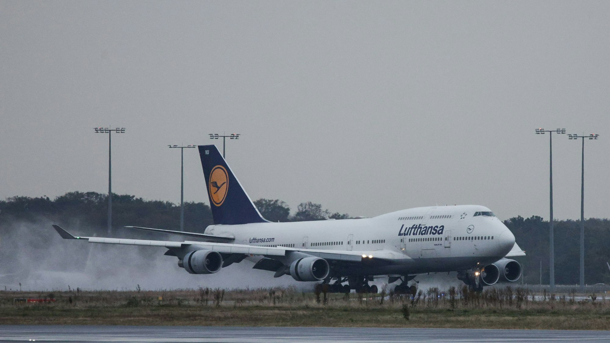 Eine Boeing 747 der deutschen Fluggesellschaft Lufthansa im Landeanflug bei einem Unwetter. Der Regen auf der Landebahn wird aufgewirbelt. (Symbolbild)